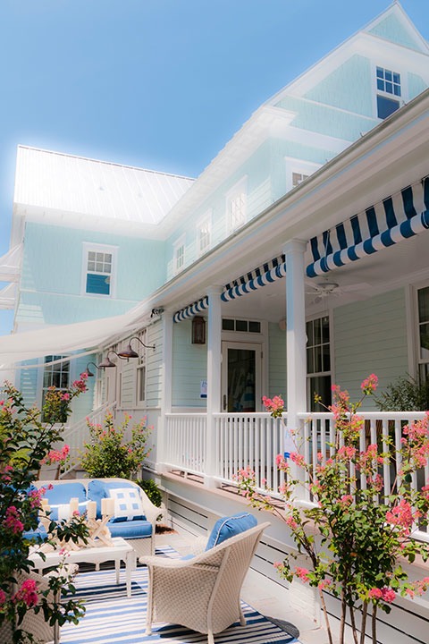 garden rooms snuggle into back corner courtyard of the 2011 Coastal Living Idea House, framed by side porch with striped canvas roll-down awnings