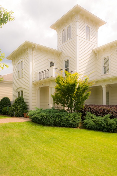 all-white Italianate home rises three stories to richly bracketed eaves spreading out against the cloud-strewn skies in the Village of Providence, Huntsville, Alabama