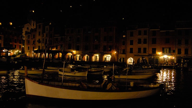 small wooden boats bob in the night waters of Portofino's harbor