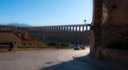 Segovia's fabulous aqueduct stretches across the town entrance as a solitary wall-mounted street lamp refracts late afternoon sunlight around the corner of heavy masonry street walls